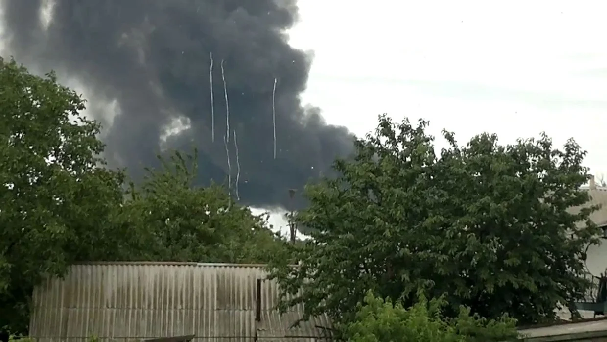 Video still showing falling debris (5 white textile rolls) from MH17, the black smoke in the background is from site 6.
